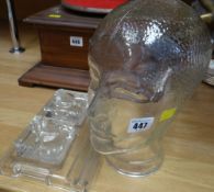 A modern glass human head sculpture together with a glass desk stand