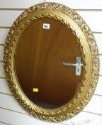 A good oval bevelled glass mirror in an ornate gilt frame
