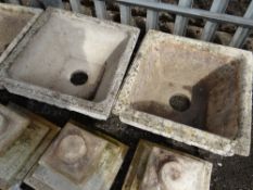 A pair of composite stone square planters on a low plinth (outside)