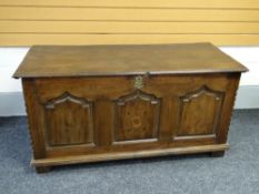 An early nineteenth century tri-panelled oak coffer with marquetry & inlaid detail on stile feet
