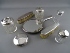 Silver dressing table items including a hand mirror, two non-matching brushes, four jars/hair tidies
