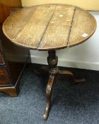 An antique circular top tripod table