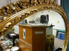 Scrolled decorated gilt framed oval wall mirror