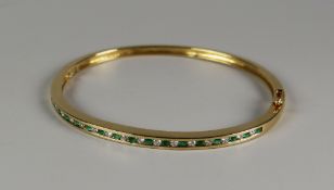 A 9CT GOLD DIAMOND & EMERALD SET BANGLE having a total of thirty-three alternating stones, 13.7grams