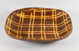 A SLIPWARE BAKING DISH WITH CREAM SLIP LATTICE DECORATION believed 19th Century, 32cms long