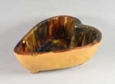 A HEART SHAPED EARTHENWARE SLIP JELLY MOULD on four corner supports and with mottle glazed interior,