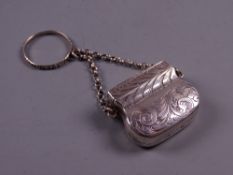 A BAG SHAPED SILVER VINAIGRETTE with scrolled decoration and with chain and safety ring,
