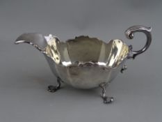 A SILVER SAUCE BOAT on three shell feet with sea scroll handle, Birmingham 1907, 4.6 troy ozs