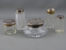 FIVE VARIOUS SILVER TOPPED GLASS DRESSING TABLE CONTAINERS including a squat example, the lid with