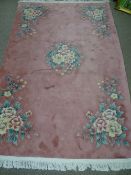 A PINK CHINESE WASHED WOOL CARPET with pastel floral pattern and tasselled ends, 260 x 184 cms