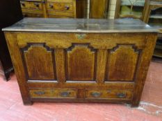 AN ANTIQUE JOINED OAK MULE CHEST having three shaped and crossbanded front panels over twin oak