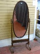 A REGENCY STYLE MAHOGANY OVAL DRESSING MIRROR with reeded and gilt highlighted decoration and cone