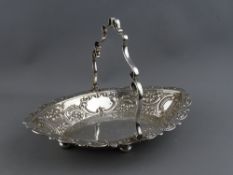 AN EMBOSSED SILVER OVAL SWING HANDLED BREAD BASKET, 28.5 cms long, Sheffield 1903, 16 troy ozs