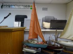 Model tug and yacht on stands and another model boat