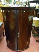 Georgian mahogany bow front two door wall hanging corner cupboard with brass 'H' hinges