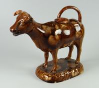 A SWANSEA POTTERY BROWN GLAZED COW-CREAMER with cover, standing over an oval base with loop-tail
