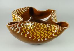 AN EWENNY POTTERY DISH BY H ELLIOTT of folded-neck form and decorated with slip trails, the base