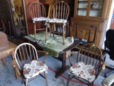 An Ercol dark wood dining table & four matching chairs