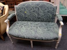 A white painted French-style two-seater settee with cushioned arms