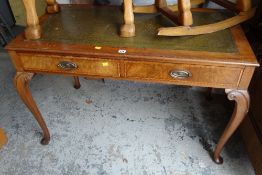 A reproduction two-drawer writing desk with tooled green leather top on cabriole supports