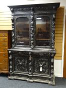 A large antique deep-carved stained dresser / bookcase cupboard carved with lion heads, including