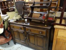 An Ercol dresser base in dark wood with two Ercol plate racks