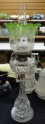 A cut glass oil lamp having a stepped base & fluted tapered column, cut glass reservoir & tinted