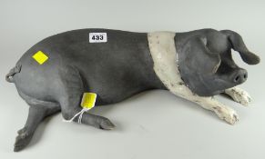 A raku pottery model of a reclining black & white pig by LAWSON C RUDGE, signed, 41cms long