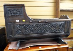 An antique carved oak rocking crib, primitively carved with foliate panels Condition Report: