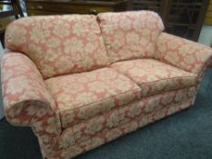 A pair of floral upholstered pink two seater sofas & a similarly upholstered wing back armchair