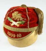 A 1909-1910 red velvet sporting cap bearing a crest with gold braid dragon & two crossed leeks,