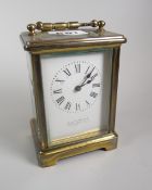A brass encased carriage clock with white enamel dial bearing Roman numerals & inscribed E J