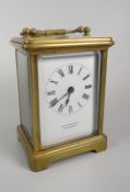 A brass encased carriage clock with white dial bearing Roman numerals & inscribed Arnold & Lewis,