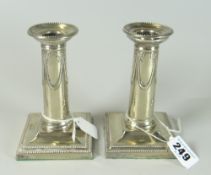 PAIR OF SILVER PLATED DWARF/SMALL CANDLESTICKS having swag and bow decoration raised on square