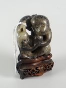 BELIEVED CHINESE BLACK & WHITE JADE CARVED MONKEY GROUP raised on carved hardwood base, 9.5cms