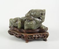 CHINESE SPINACH JADE STUDY OF A RECUMBENT LION DOG raised on carved hardwood base, 8cms high