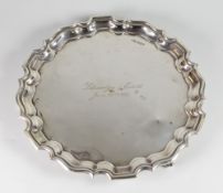 GEORGE V SILVER PIE CRUST EDGE SALVER, raised on three scroll feet and engraved 