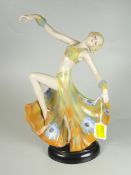 A CONTINENTAL PORCELAIN ART DECO FIGURE of a dancing lady in long floral dress and with leg kick and