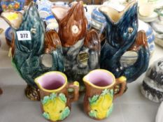 Three Majolica pottery fish glug jugs & two fruit decorated Majolica jugs