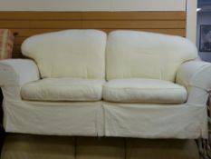 A modern cream upholstered two-seater settee with swept arms