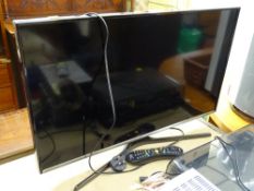 A Samsung flatscreen TV on stand with remote E/T