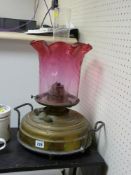 A Victorian, brass reservoir base oil lamp with cranberry glass shade