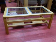 Modern light wood coffee table with twin glass inserts and having a lower base shelf