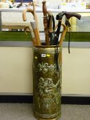 Repousse brass stickstand and contents including a modern folding shooting stick, a Malacca cane