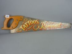 Vintage timber saw with painted detail saying 'Tattoos Removed'