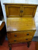Small compact writing bureau with upper twin doors and lower graduated drawers