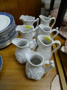 Seven white parian unglazed jugs