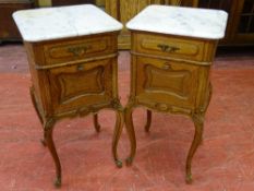 A PAIR OF FRENCH OAK BEDSIDE CABINETS with white marble tops and cupboard interiors having carved