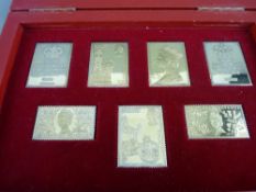 A CASED SET OF SEVEN SILVER GILT COMMEMORATIVE STAMPS by hallmark replicas commemorating the 25th
