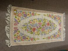 A KASHMIRI CHAIN HAND STITCH RUG, tassel ended cream ground with central floral cameo, 120 x 69 cms